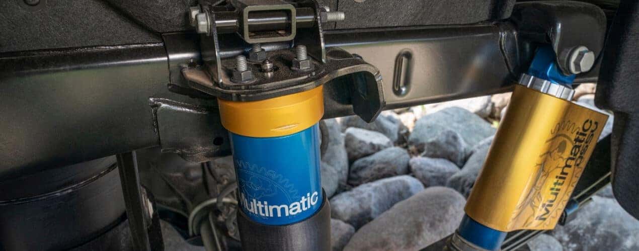 A close-up shows the yellow and blue multimatic suspension in a 2025 Chevy Colorado ZR2 Bison.