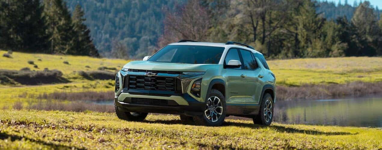 A green 2025 Chevy Equinox ACTIV parked on a grassy hill.