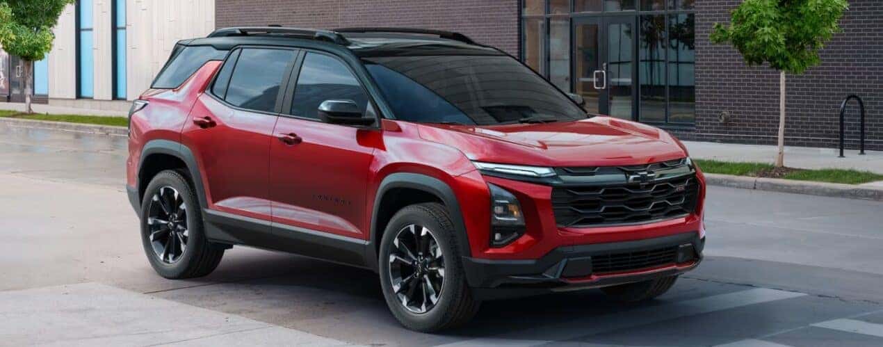 A red 2025 Chevy Equinox RS driving on a city street.