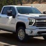 A white 2025 Chevy Silverado 2500 Z71 is shown driving on a highway.