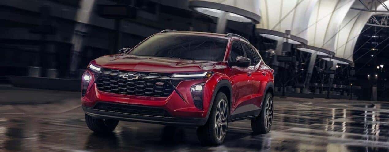 A red 2025 Chevy Trax RS is shown driving on a rainy night.