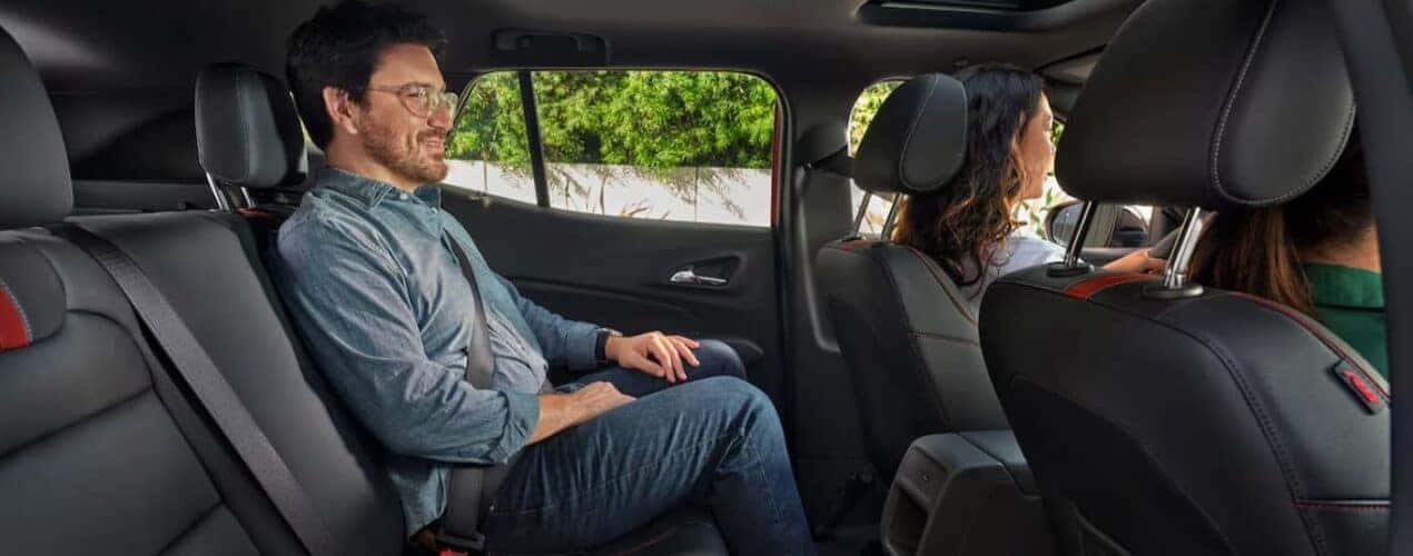 A passenger is shown sitting in the black interior of a 2025 Chevy Trax.