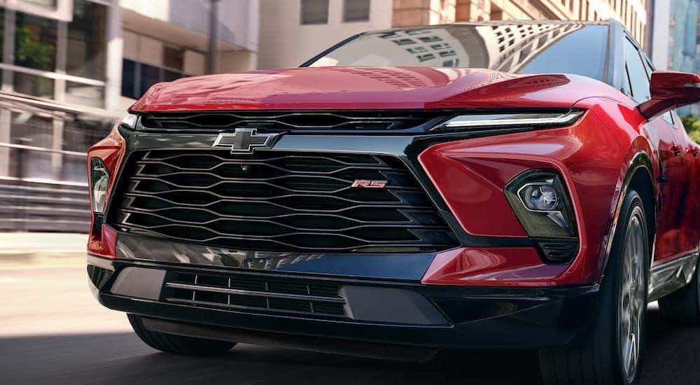 Front angle view of a red 2025 Chevy Blazer RS driving through a city.