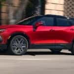 A red 2025 Chevy Blazer for sale near Colonie driving down a road.