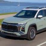 A green 2025 Chevy Equinox ACTIV driving near a lake.