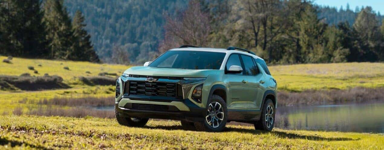 A green 2025 Chevy Equinox ACTIV is shown parked near a pond.