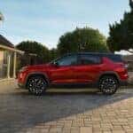 A red 2025 Chevy Equinox RS is parked on a driveway in front of a garage.