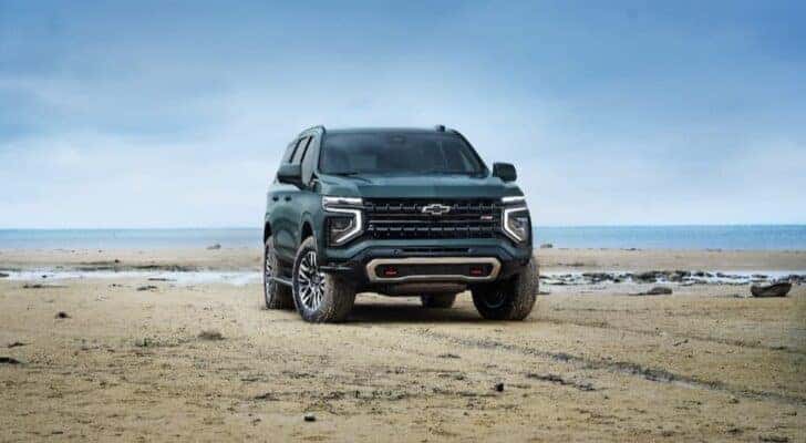 A green 2025 Chevy Tahoe Z71 is shown parked on a beach.