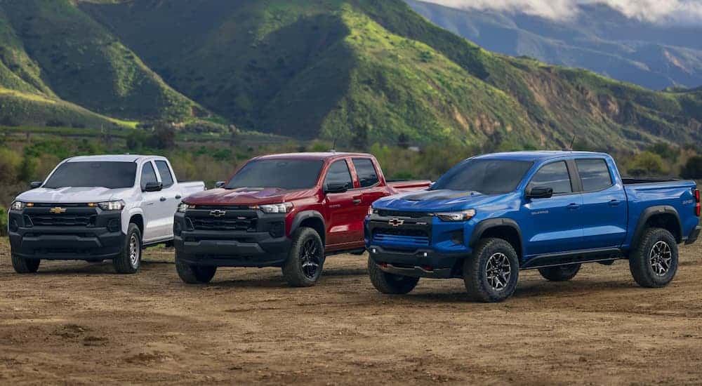Three 2025 Chevy Colorado trucks for sale in Albany parked on dirt.