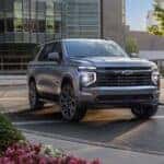 A grey 2025 Chevy Tahoe RST for sale near Colonie driving through a city.