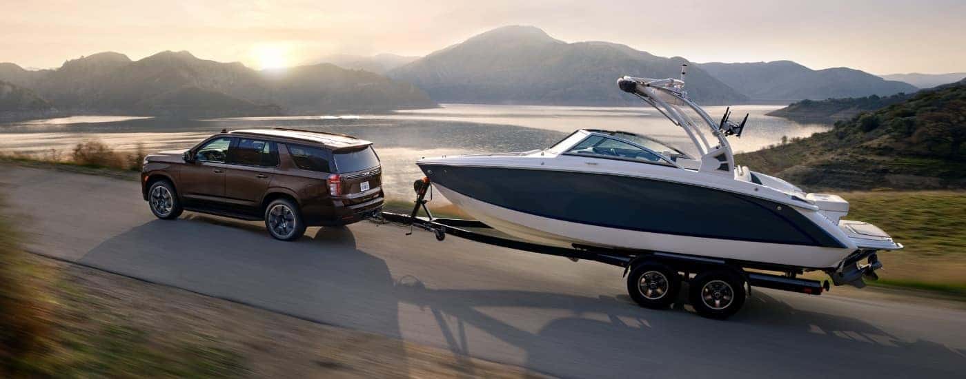 A brown 2022 Chevy Tahoe is shown from the side while towing a boat.