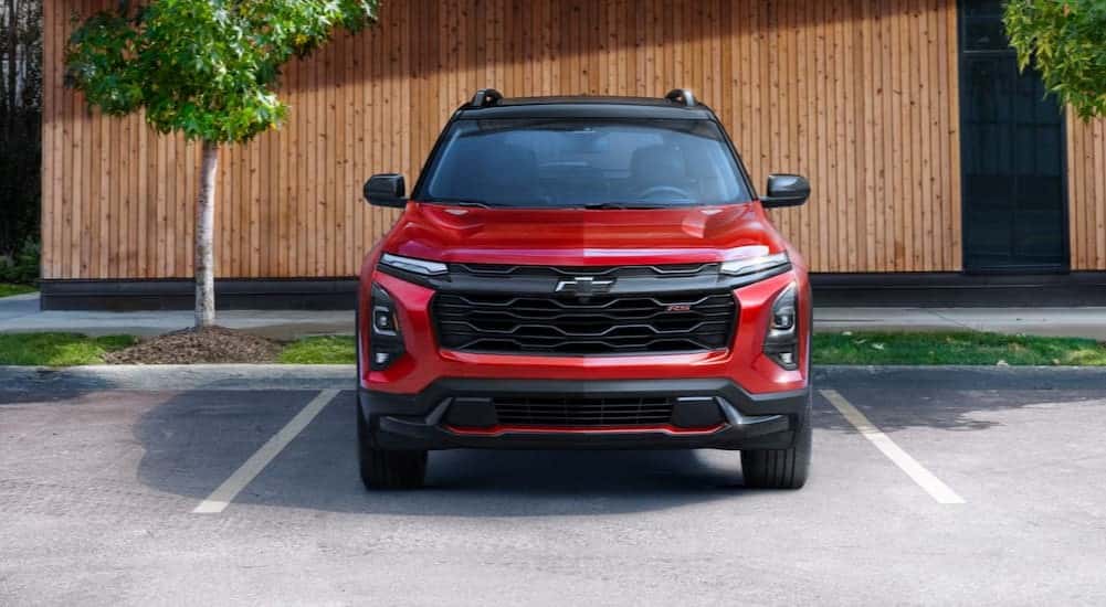 A red 2025 Chevy Equinox RS parked near trees.
