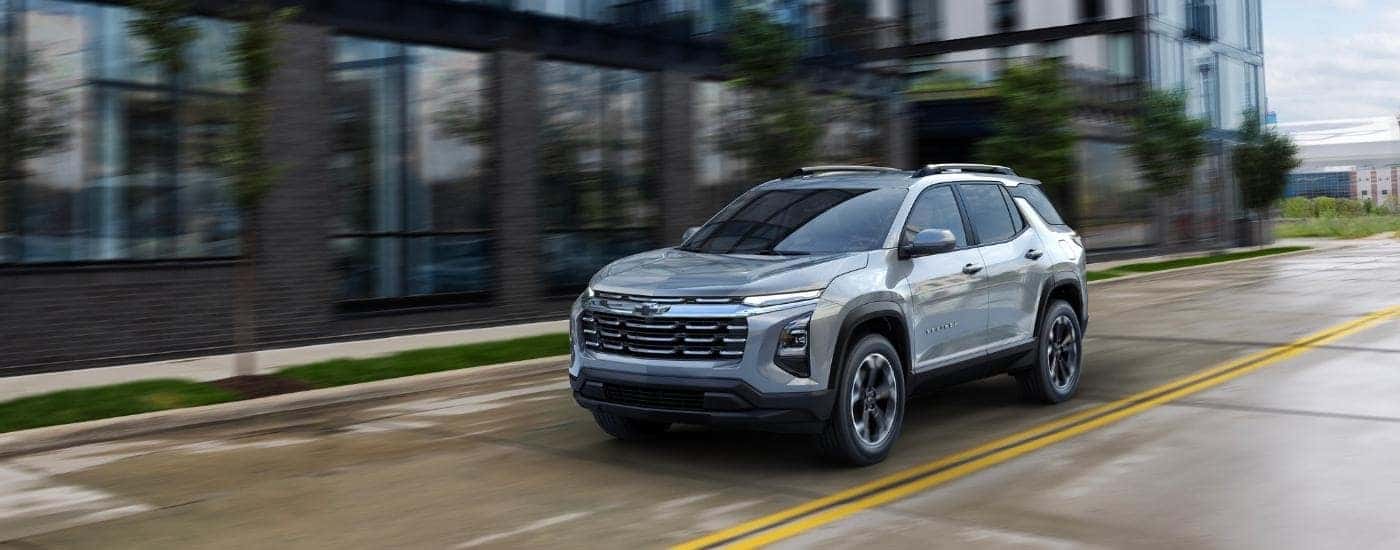 Grey 2025 Chevy Equinox LT driving past a tall building.
