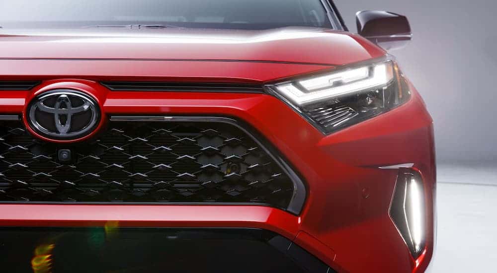 Close-up on the headlights and grille of a red 2025 Toyota RAV4.