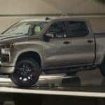 A grey 2025 Chevy Silverado 1500 LT parked in a showroom.