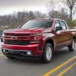 A red 2019 Chevy Silverado 1500 RST for sale near Schenectady driving by a lake.