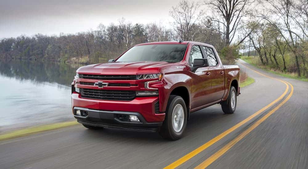 A red 2019 Chevy Silverado 1500 RST for sale near Schenectady driving by a lake.
