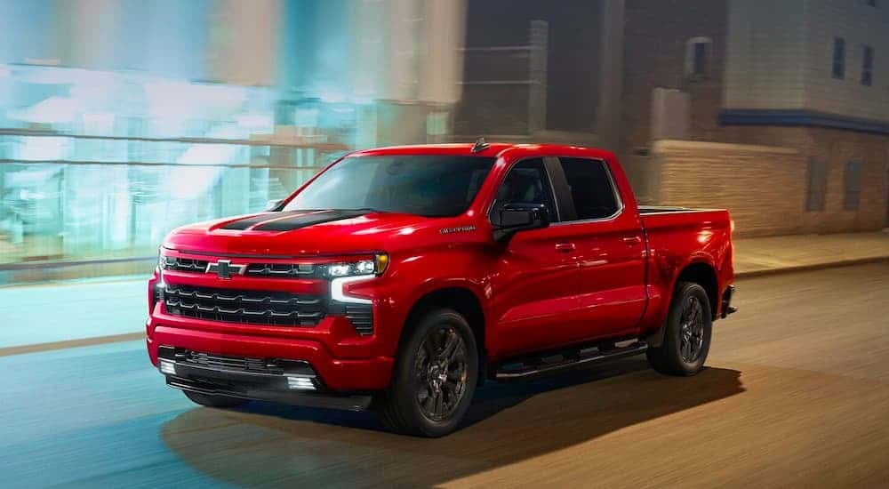 A red 2023 Chevy Silverado 1500 RST driving through a city.