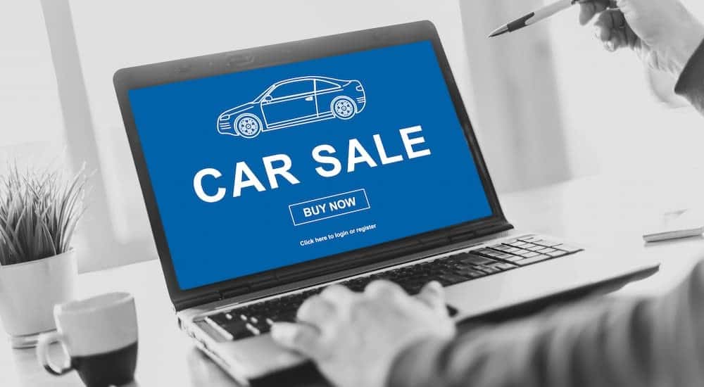 Person using a laptop looking for a used car dealer in Albany.