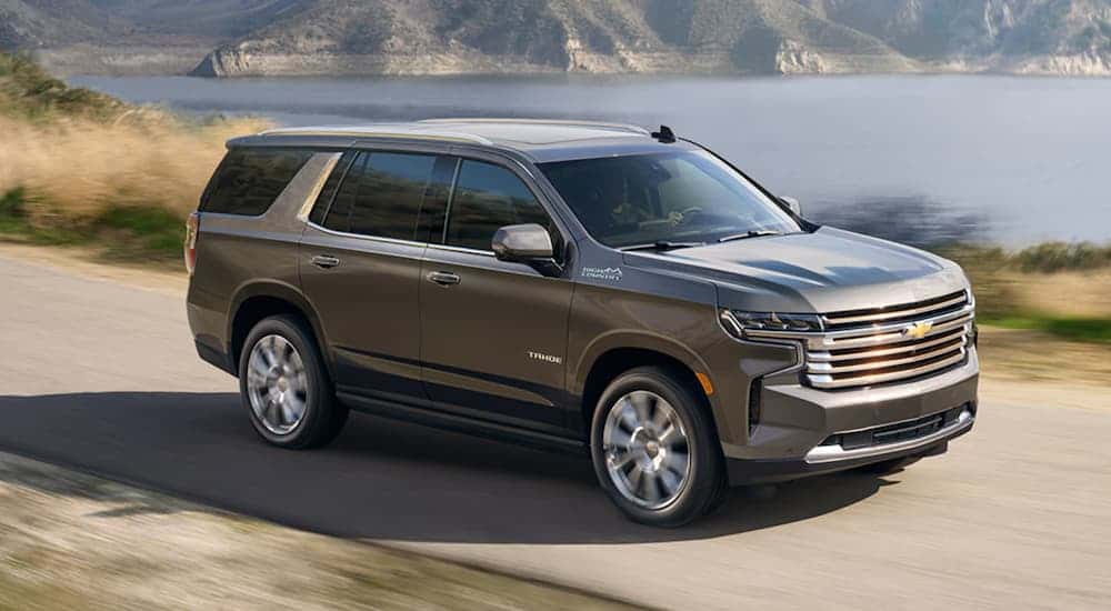 A gray 2021 Chevy Tahoe High Country driving near a lake.