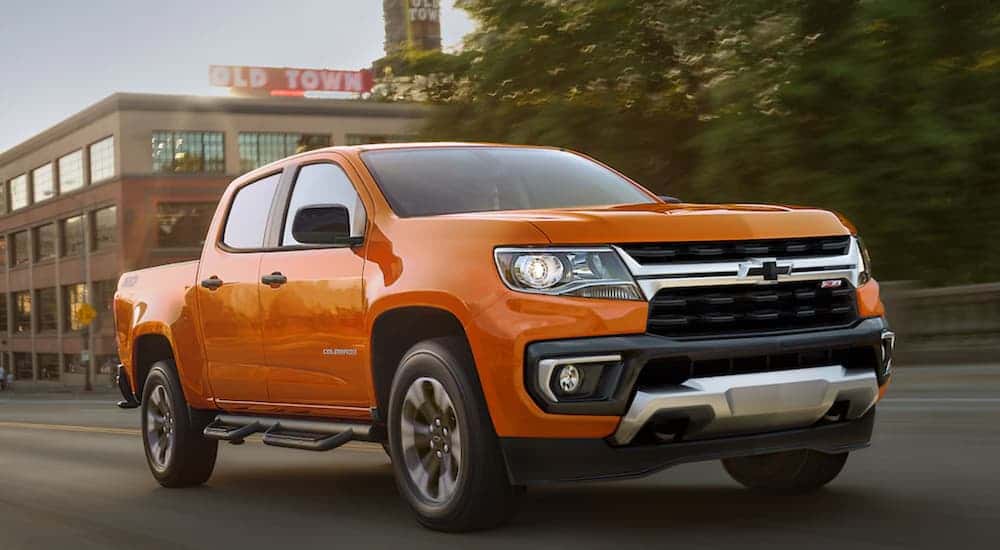 An orange 2021 Chevy Colorado Z71 driving in a city.