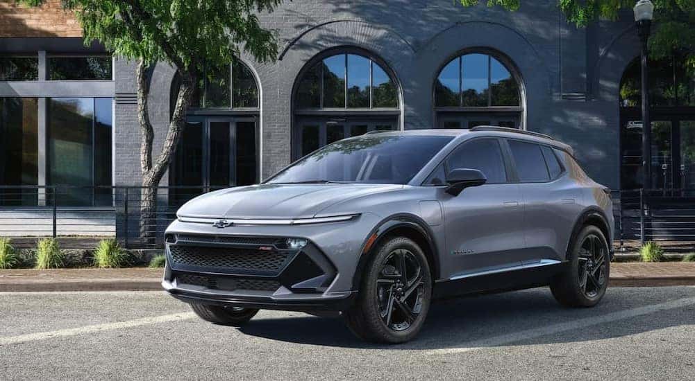 A silver 2025 Chevy Equinox EV RS parked near a building.