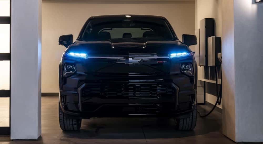 A black 2025 Chevy Silverado EV charging in a garage.