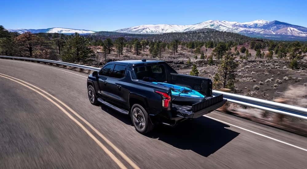 A black 2025 Chevy Silverado EV RST driving on a highway.