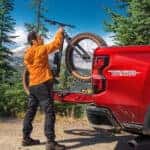 A red 2023 used Chevy Colorado for sale being loaded with a bike.