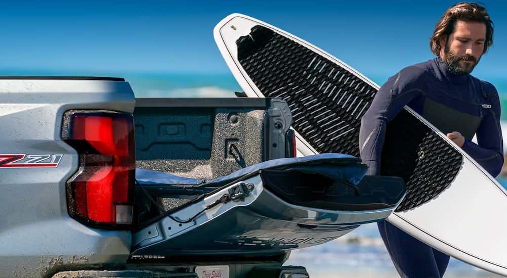A silver 2023 Chevy Colorado having a surf board loaded up.