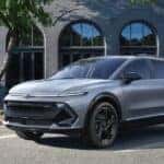 A silver 2025 Chevy Equinox EV RS parked in a city.
