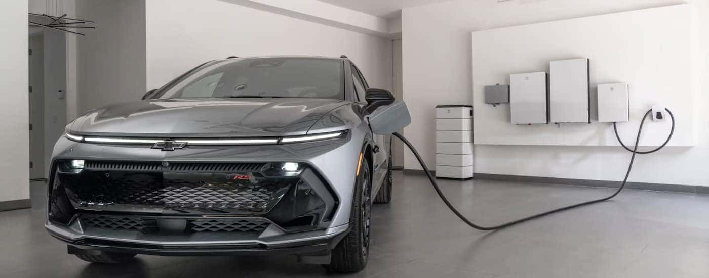A silver 2025 Chevy Equinox EV charging in a garage