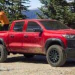 A red 2025 Chevy Colorado Trail Boss parked on a dirt road.
