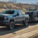 A gray 2025 Chevy Silverado 2500 ZR2 towing a trailer off-road.