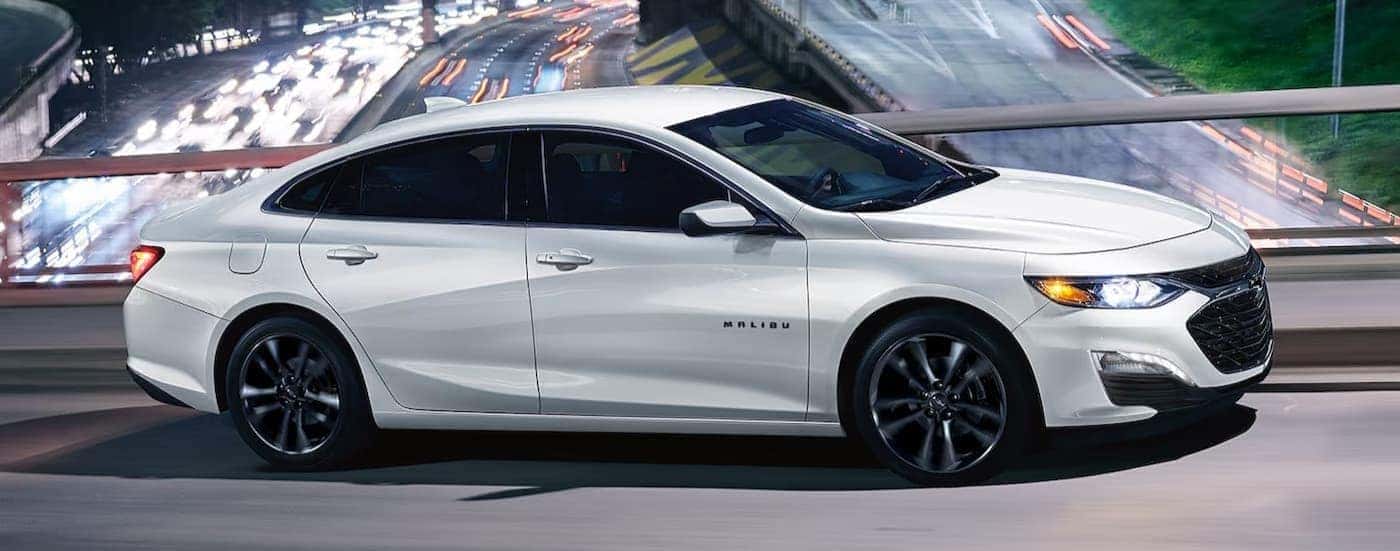 A white 2025 Chevy Malibu driving on a bridge.