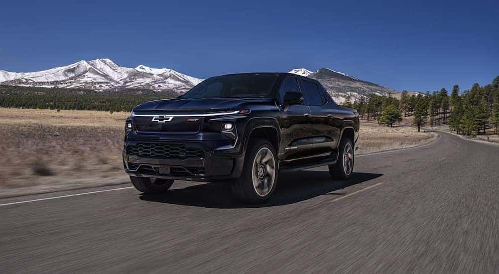 A blue 2025 Chevy Silverado EV RST driving on a highway.