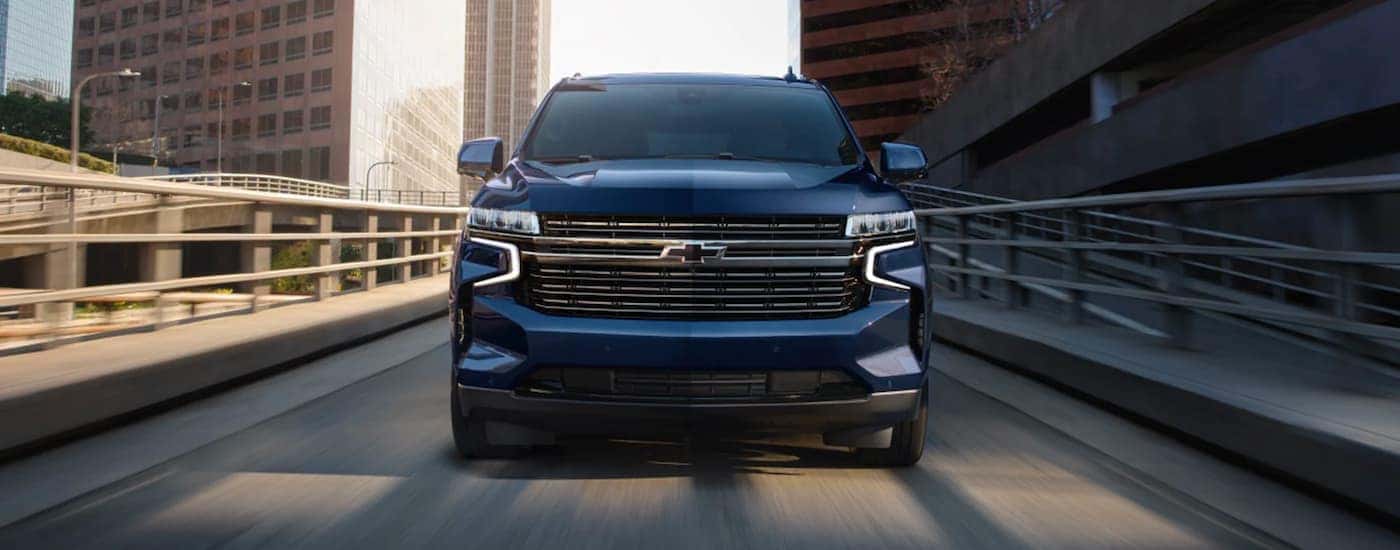 A blue 2023 Chevy Tahoe driving after viewing a used Chevy Tahoe for sale in Albany.