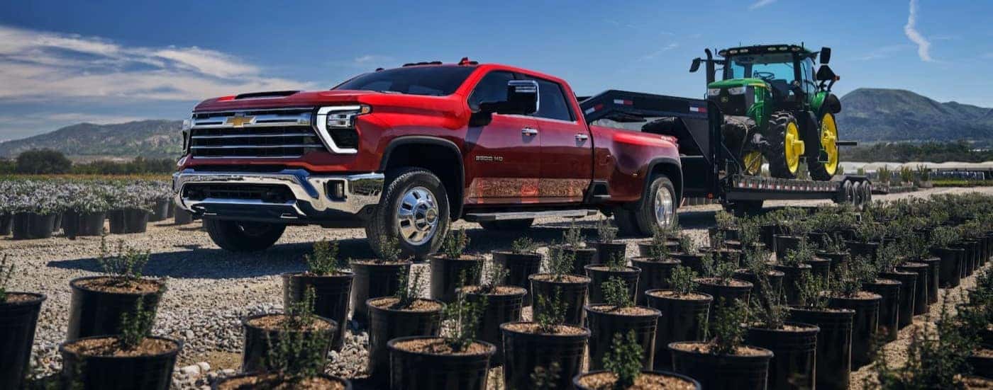 A red 2025 Chevy Silverado 3500 HD towing a trailer.