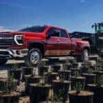A red 2025 Chevy Silverado 3500 towing a tractor
