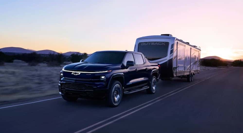 A black 2025 Chevy Silverado EV RST towing a trailer.