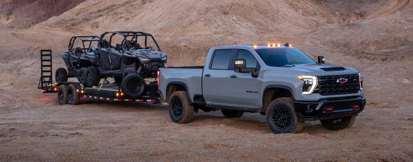 Grey 2025 Chevy Silverado 2500 HD vs 2025 GMC Sierra 2500 HD towing ATVs