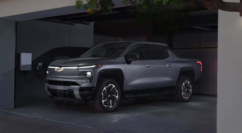 A silver 2025 Chevy Silverado EV charging in a garage