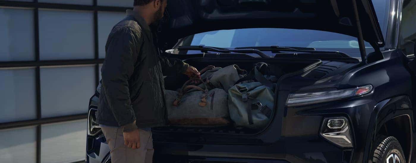 Man putting bags into the frunk of a black 2025 Chevy Silverado EV