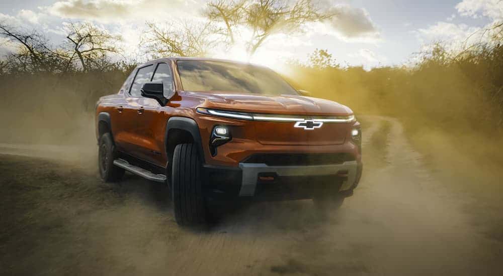 A red 2025 Chevy Silverado EV off-roading on a dirt road