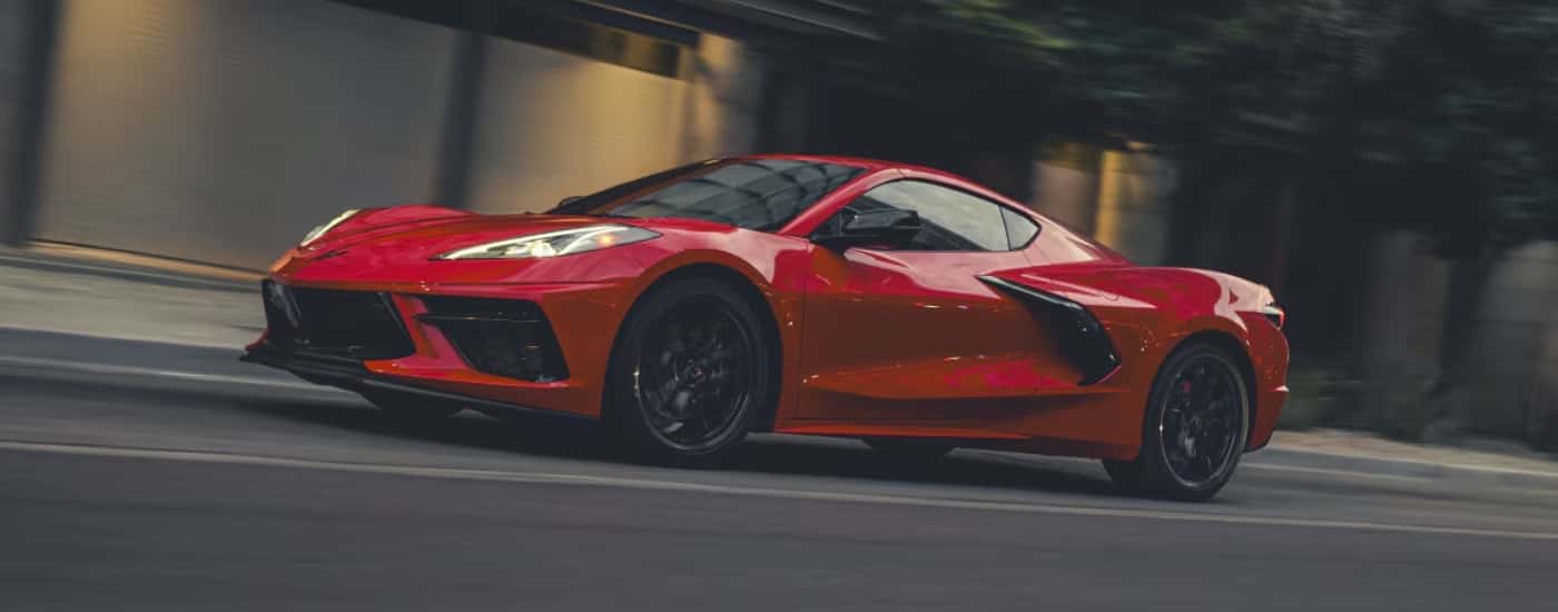 A red 2026 Chevy Corvette driving on a city street.