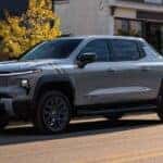 A silver 2025 Chevy Silverado EV parked in a city.