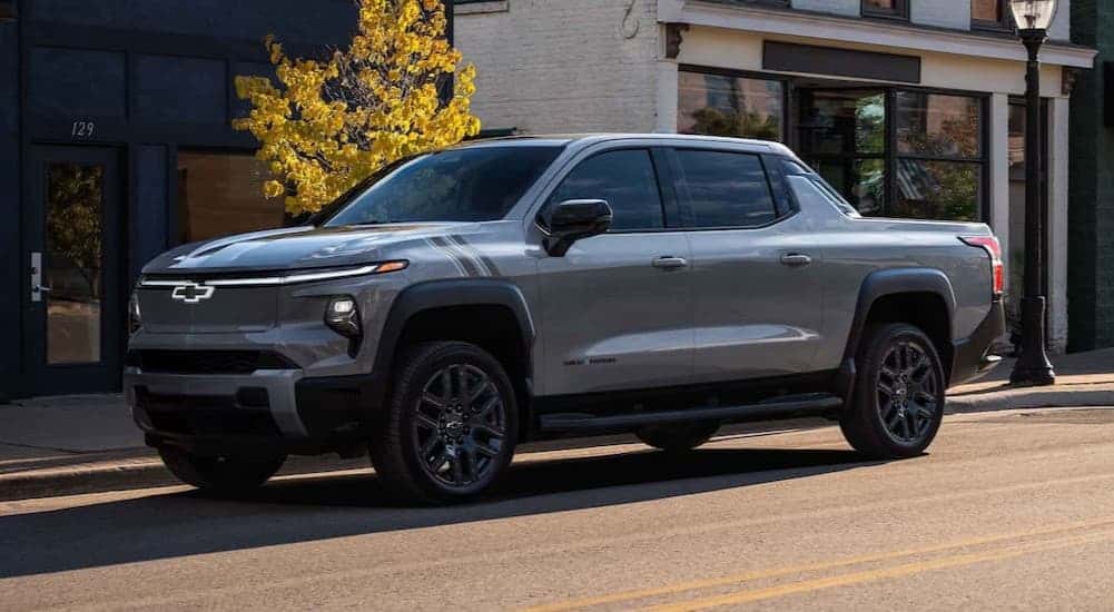A silver 2025 Chevy Silverado EV parked in a city.