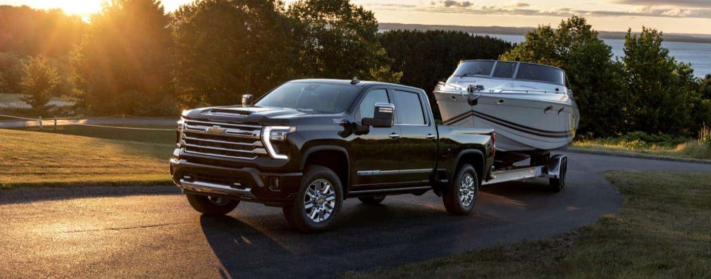 A black 2025 Chevy Silverado 2500 HD High Country towing a boat