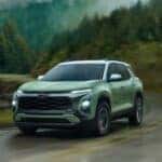 Green 2025 Chevy Equinox RS driving up a mountain road.