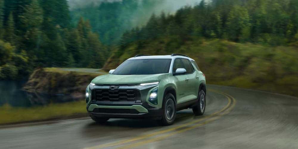 Green 2025 Chevy Equinox RS driving up a mountain road.